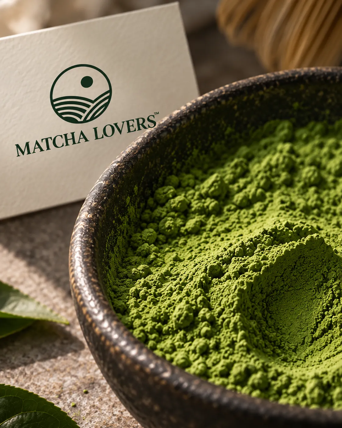 Cuenco metálico lleno de matcha recién molido, con la tarjeta de la marca al lado